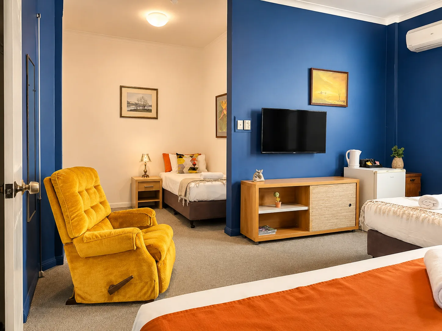 Bedroom with recliner, TV and bar fridge — Family Room Standard at Vine Valley Inn Cessnock