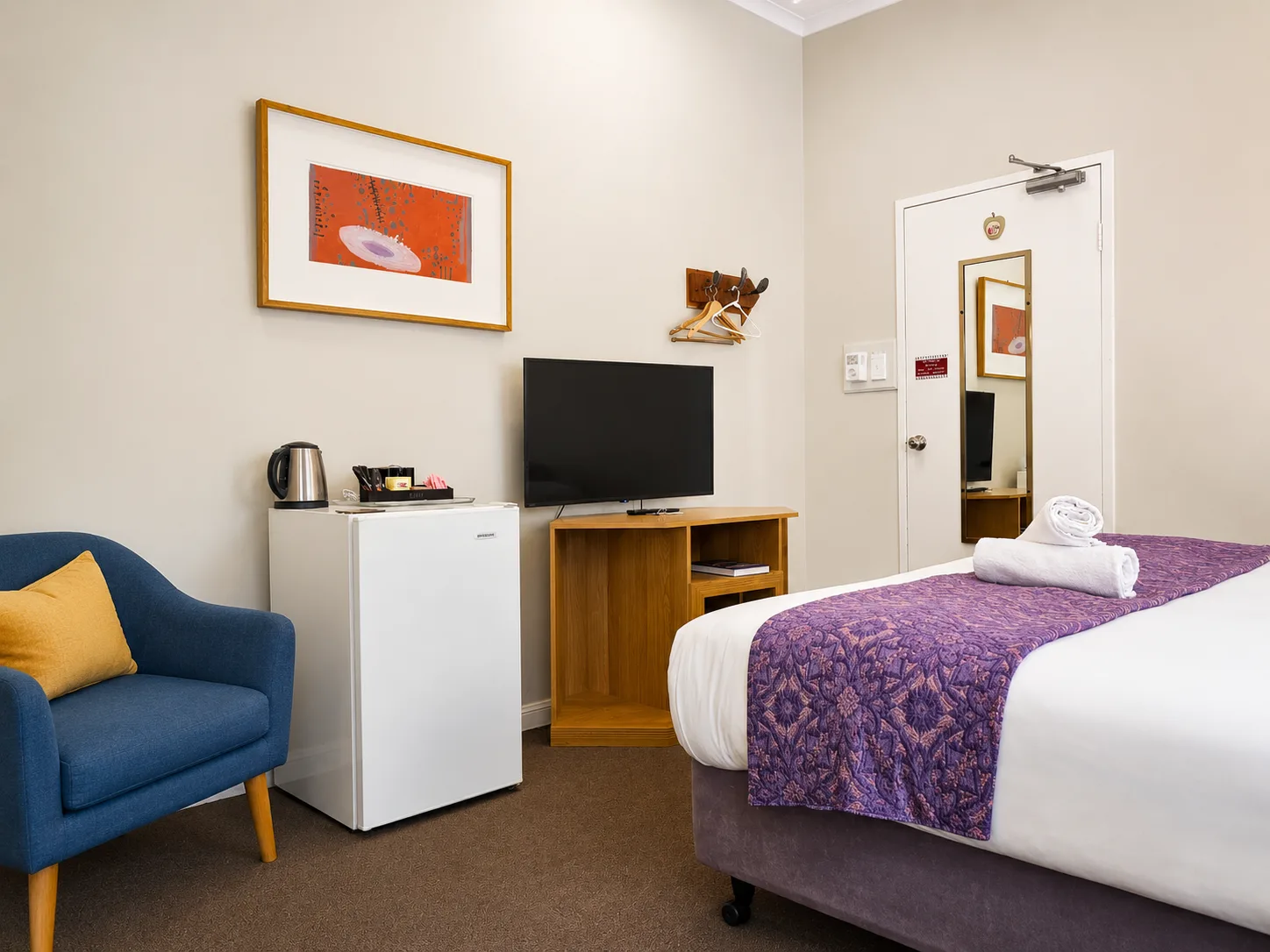 Bedroom with armchair and TV — King Room at Vine Valley Inn Cessnock
